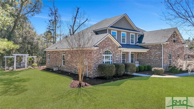 view of front facade featuring brick siding, a front yard, and a pergola