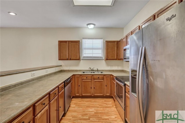 kitchen featuring stainless steel appliances, brown cabinetry, light wood-type flooring, and a sink