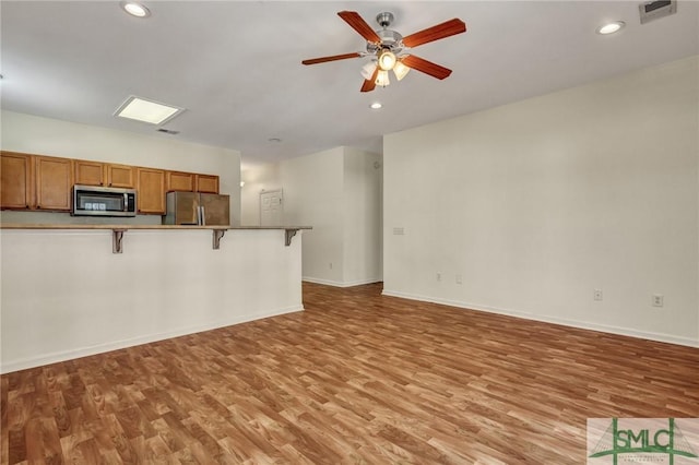 unfurnished living room featuring recessed lighting, visible vents, light wood-style flooring, a ceiling fan, and baseboards