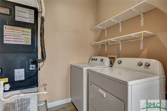 clothes washing area with laundry area, wood finished floors, baseboards, heating unit, and washing machine and clothes dryer