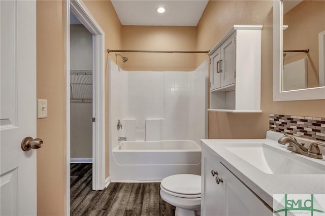 full bathroom with tasteful backsplash, toilet, wood finished floors, vanity, and shower / bathing tub combination