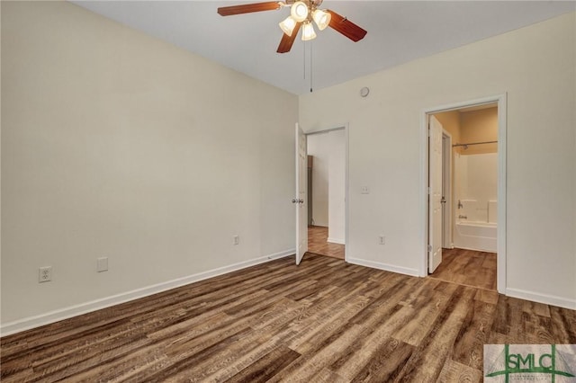 unfurnished bedroom featuring ensuite bathroom, wood finished floors, a ceiling fan, and baseboards