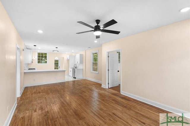 unfurnished living room with ceiling fan, recessed lighting, wood finished floors, and baseboards