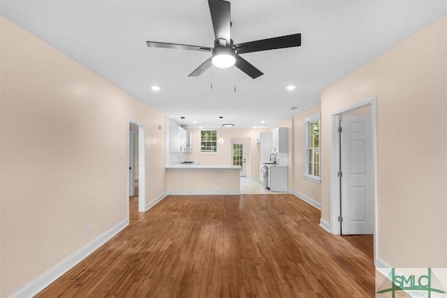 unfurnished living room with recessed lighting, a sink, ceiling fan, wood finished floors, and baseboards