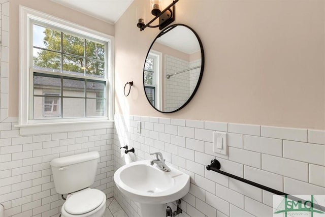 bathroom featuring a wainscoted wall, a sink, tile walls, and toilet