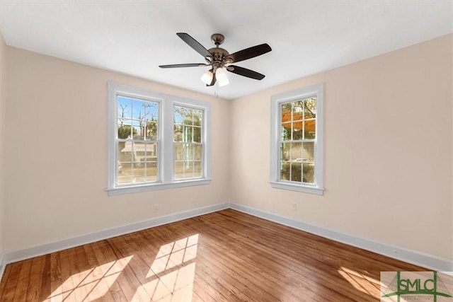 empty room featuring baseboards, wood-type flooring, a ceiling fan, and a healthy amount of sunlight