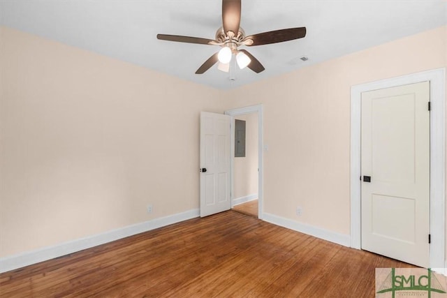 unfurnished room featuring visible vents, wood finished floors, electric panel, and baseboards