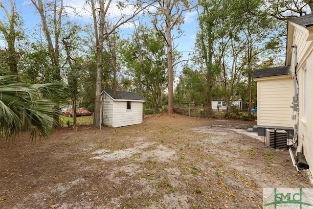 view of yard featuring a storage shed, fence, and an outdoor structure