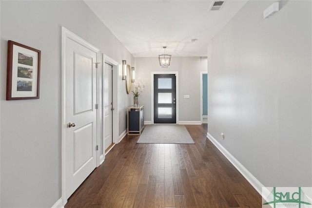 entrance foyer with dark wood-style floors, baseboards, visible vents, and a notable chandelier