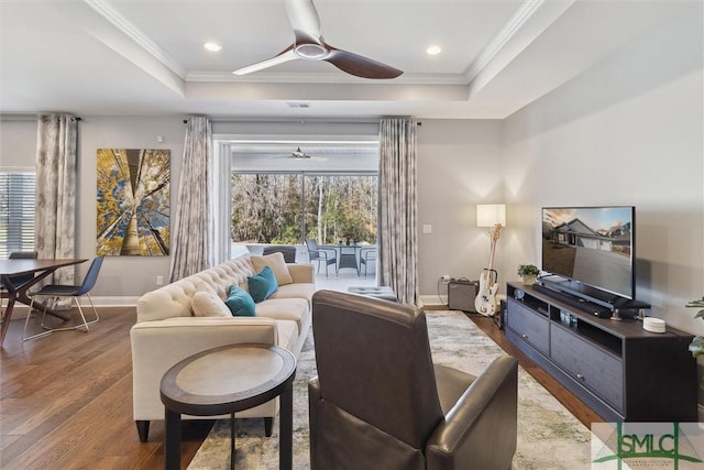 living area featuring ornamental molding, wood finished floors, a raised ceiling, and a wealth of natural light