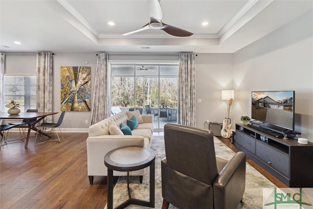 living area featuring ceiling fan, a tray ceiling, crown molding, and wood finished floors