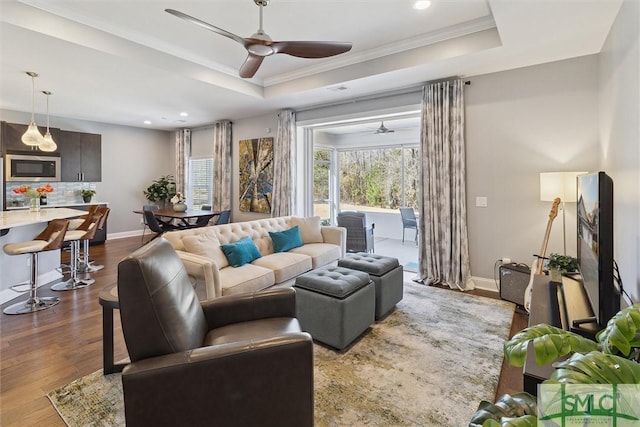 living room with dark wood-style floors, baseboards, a raised ceiling, and a ceiling fan