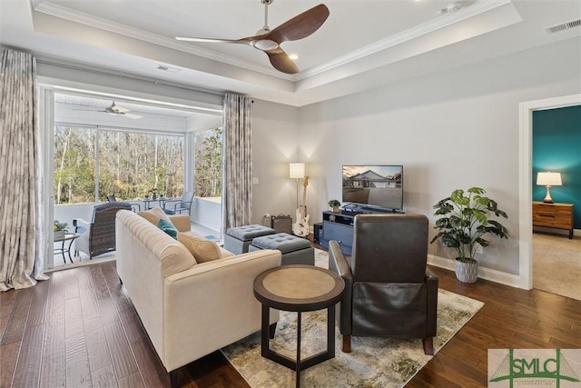 living area featuring a ceiling fan, a raised ceiling, visible vents, and wood finished floors