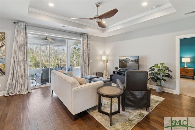 living area featuring a ceiling fan, visible vents, a raised ceiling, and dark wood finished floors