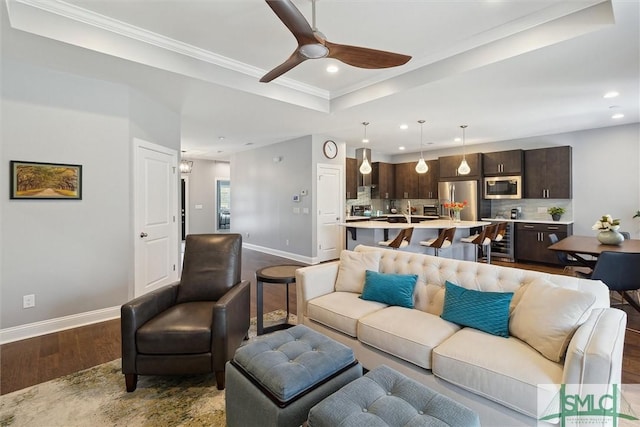 living area featuring dark wood-style flooring, recessed lighting, a raised ceiling, a ceiling fan, and baseboards