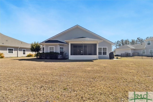 rear view of property featuring a yard, fence, and a sunroom