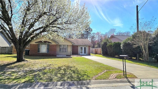 ranch-style home featuring french doors, brick siding, fence, driveway, and a front lawn