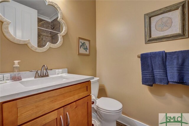 bathroom featuring baseboards, vanity, and toilet