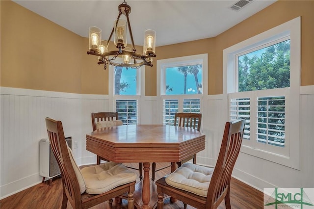 dining space featuring dark wood-style floors, a healthy amount of sunlight, visible vents, and a chandelier