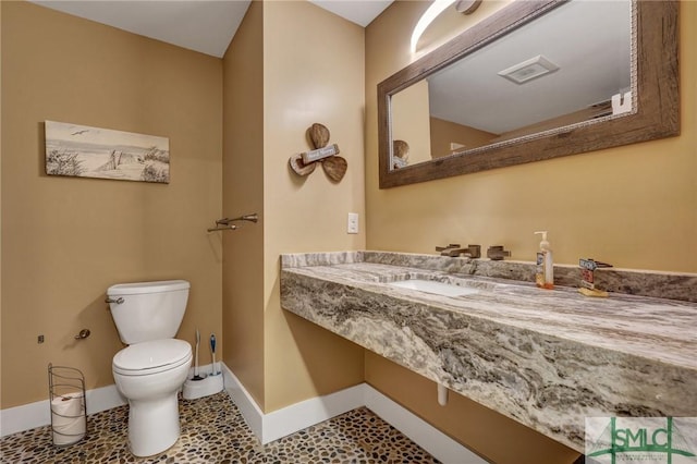 half bath featuring tile patterned flooring, toilet, and baseboards