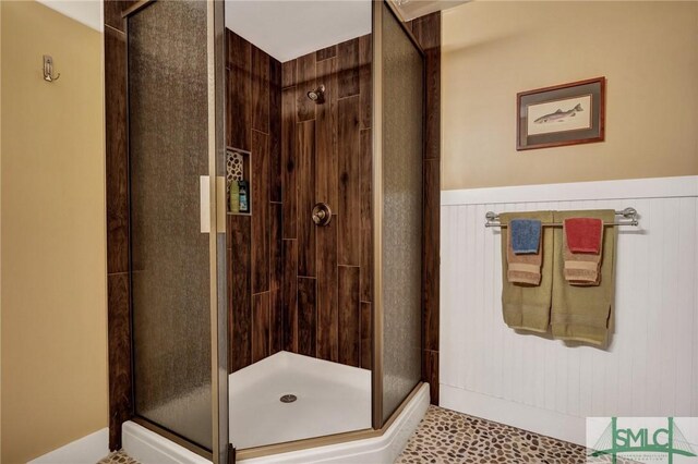 full bathroom featuring a stall shower and wainscoting