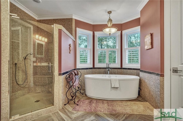 full bath with a stall shower, a wainscoted wall, crown molding, a freestanding tub, and tile walls