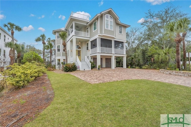 back of house with ceiling fan, a balcony, a garage, decorative driveway, and a lawn