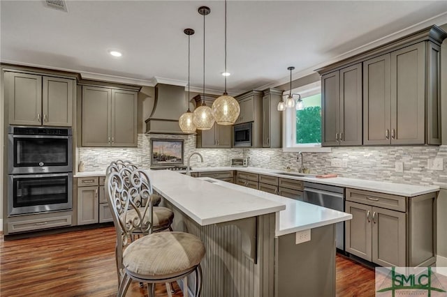 kitchen featuring a kitchen island with sink, stainless steel appliances, dark wood-type flooring, a sink, and custom range hood