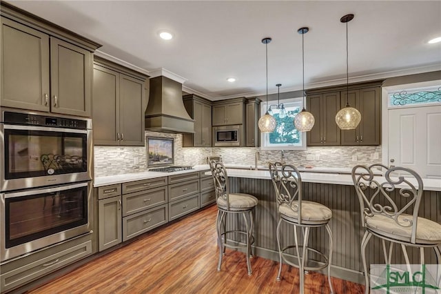 kitchen with custom range hood, appliances with stainless steel finishes, a kitchen breakfast bar, light countertops, and light wood-style floors