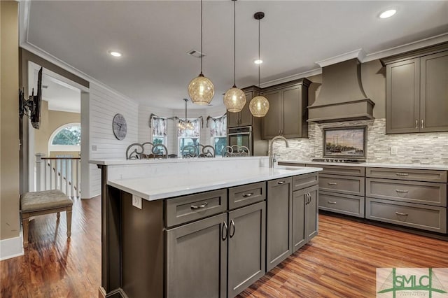 kitchen featuring crown molding, light countertops, a sink, wood finished floors, and premium range hood