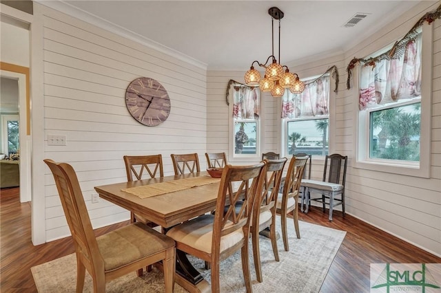 dining space with a notable chandelier, visible vents, wood finished floors, and ornamental molding