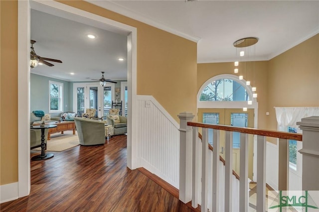 hallway featuring an inviting chandelier, ornamental molding, wood finished floors, and an upstairs landing