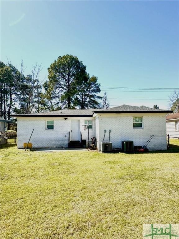 back of house featuring central air condition unit, a lawn, and brick siding