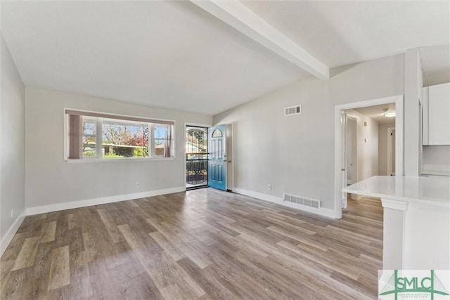 spare room featuring lofted ceiling with beams, light wood-style floors, and visible vents