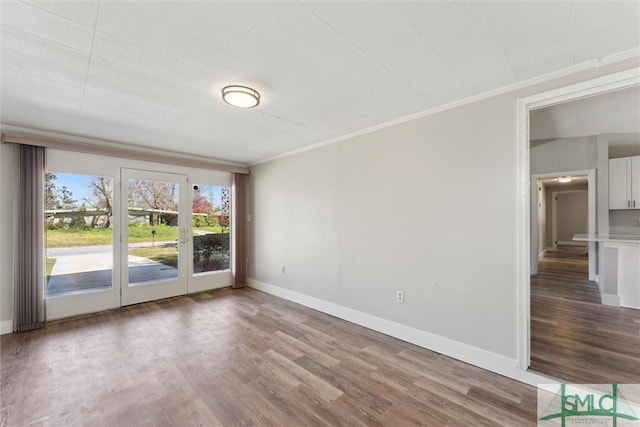 empty room with baseboards, ornamental molding, and wood finished floors