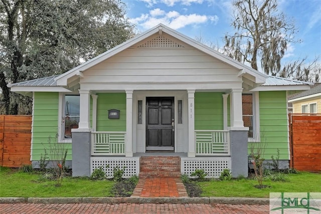 bungalow-style house featuring covered porch, fence, and metal roof