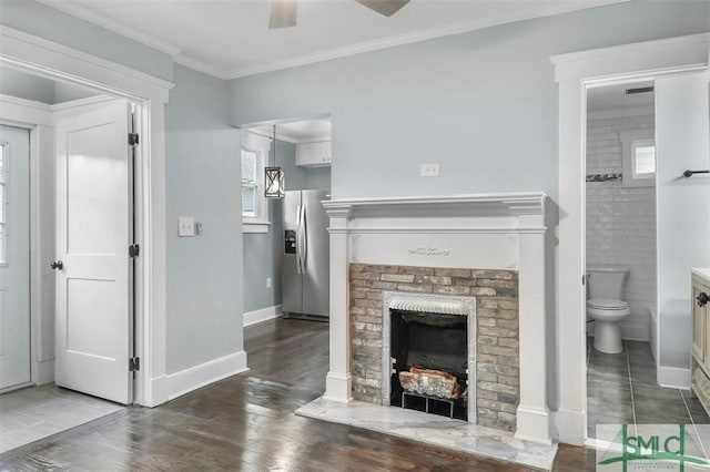 living area with ornamental molding, a fireplace, wood finished floors, and baseboards