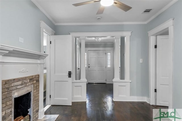 foyer entrance with a brick fireplace, visible vents, wood finished floors, and ornamental molding