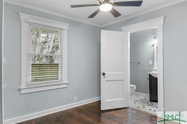 unfurnished bedroom featuring wood finished floors, a ceiling fan, baseboards, ensuite bath, and crown molding