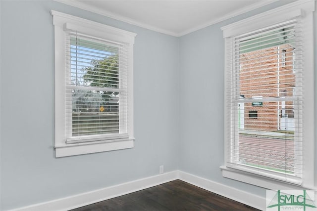 spare room with ornamental molding, dark wood-type flooring, and baseboards