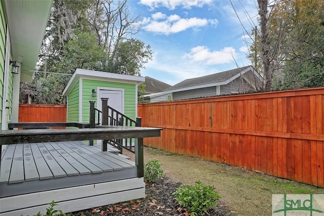 wooden terrace with an outbuilding, a fenced backyard, and a storage unit