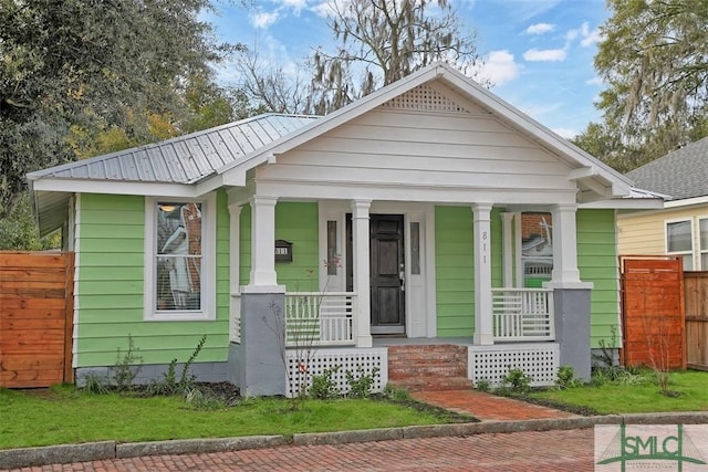 bungalow-style home featuring a porch, metal roof, and fence