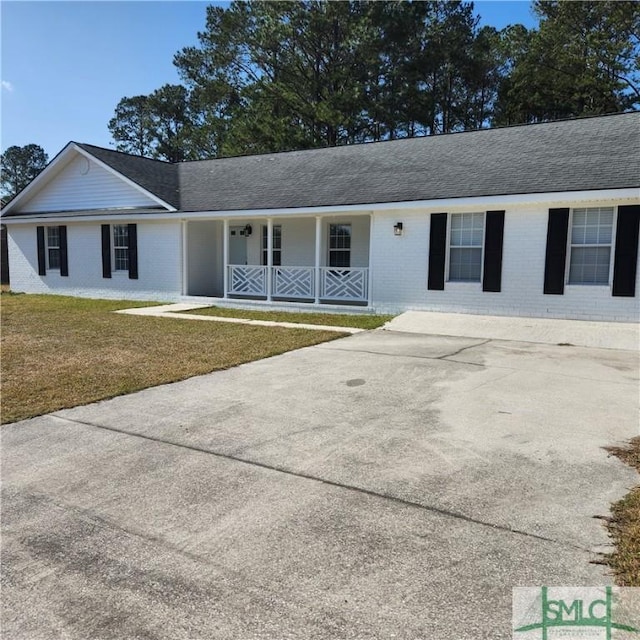 single story home featuring a porch, brick siding, a front lawn, and driveway