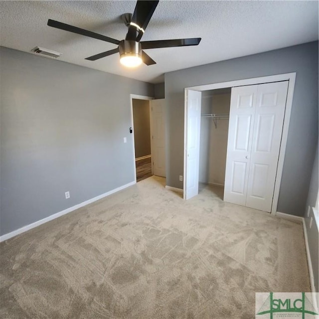 unfurnished bedroom with a closet, visible vents, light colored carpet, and baseboards