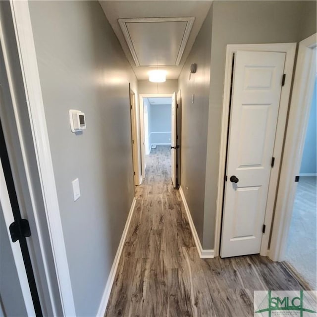 hallway with attic access, wood finished floors, and baseboards