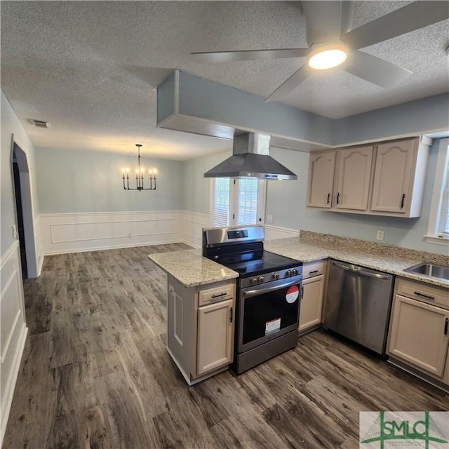 kitchen featuring visible vents, dark wood finished floors, a peninsula, stainless steel appliances, and wall chimney range hood