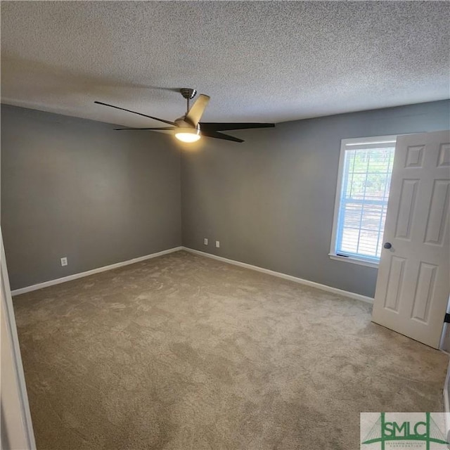 carpeted spare room featuring baseboards, a textured ceiling, and a ceiling fan