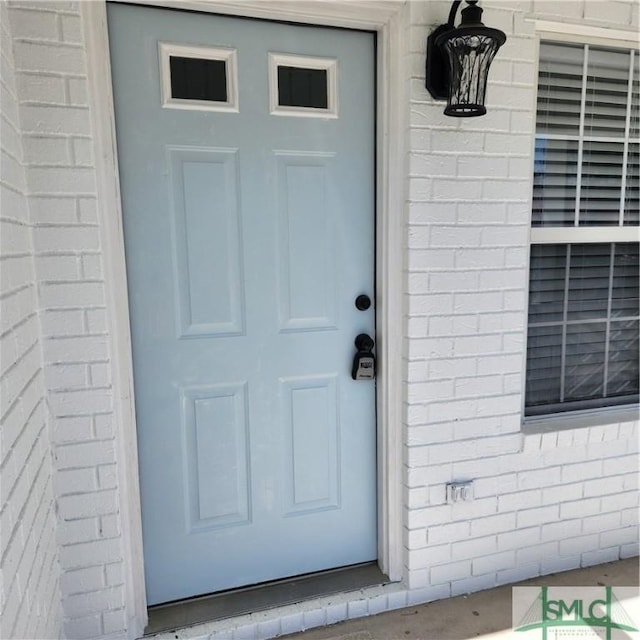 view of exterior entry featuring brick siding