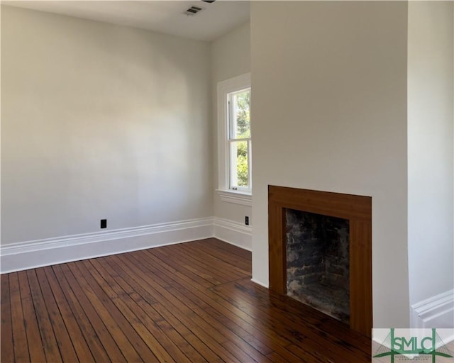 unfurnished living room featuring visible vents, baseboards, dark wood-style flooring, and a fireplace