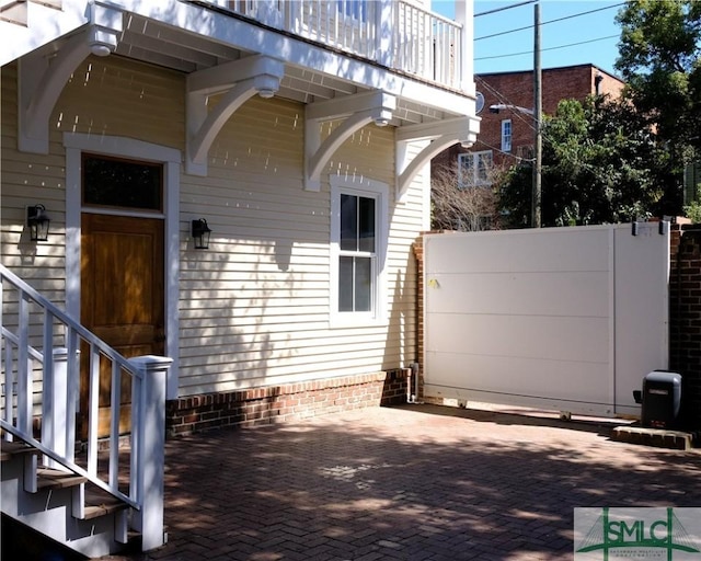 doorway to property featuring a balcony, a patio, and fence